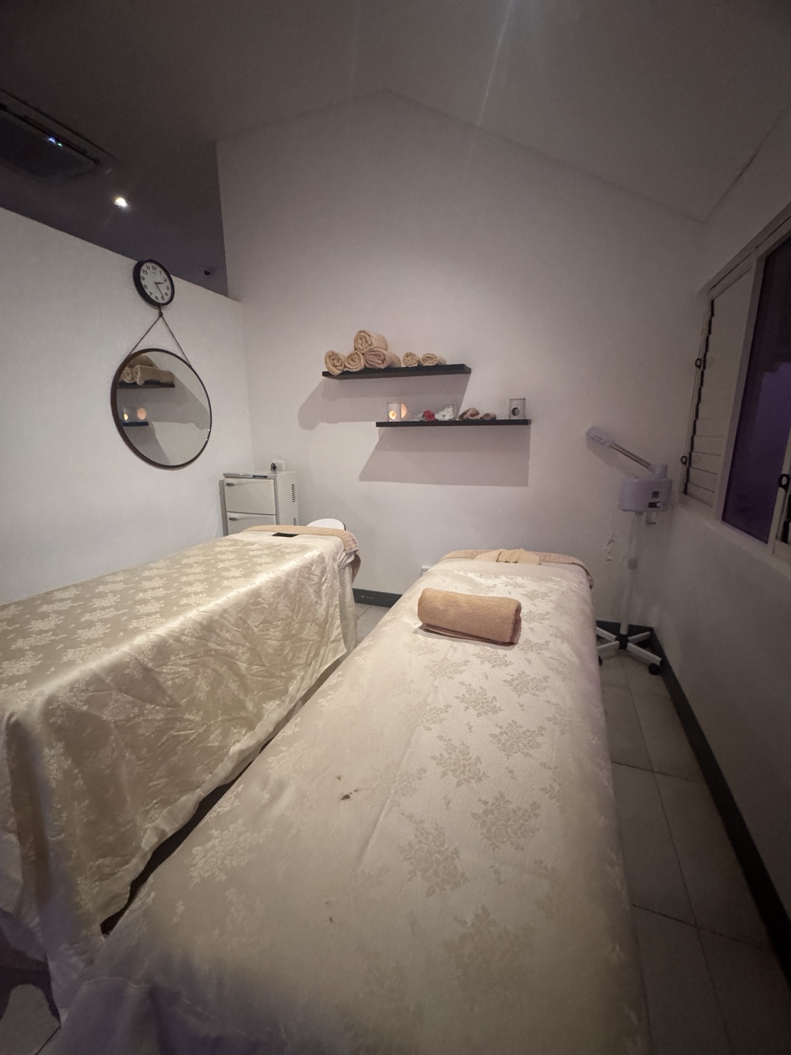 Second spa treatment room with two beds, a glass door and a partition that stops below the ceiling