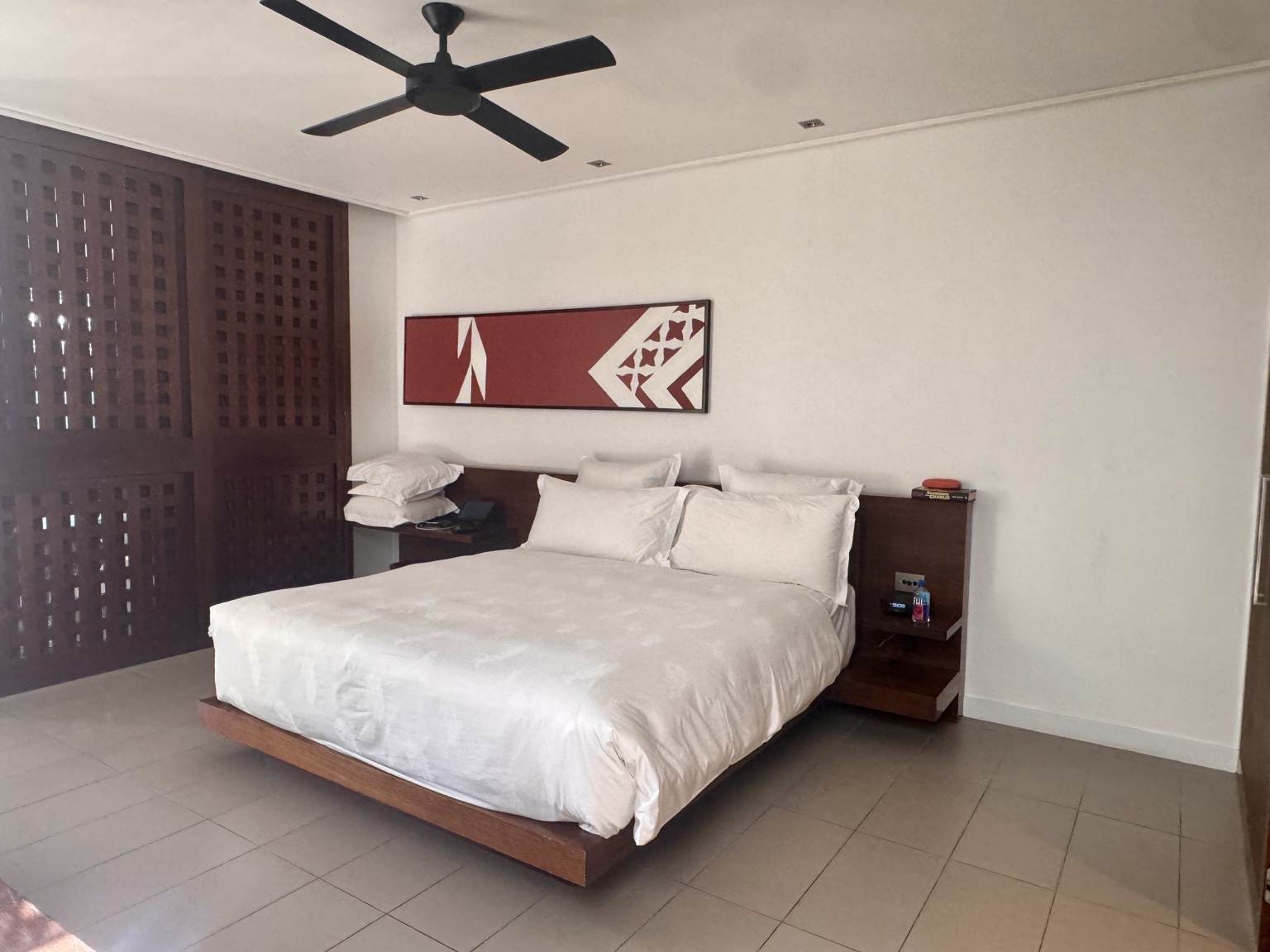 The main bedroom, with timber screens and a ceiling fan.
